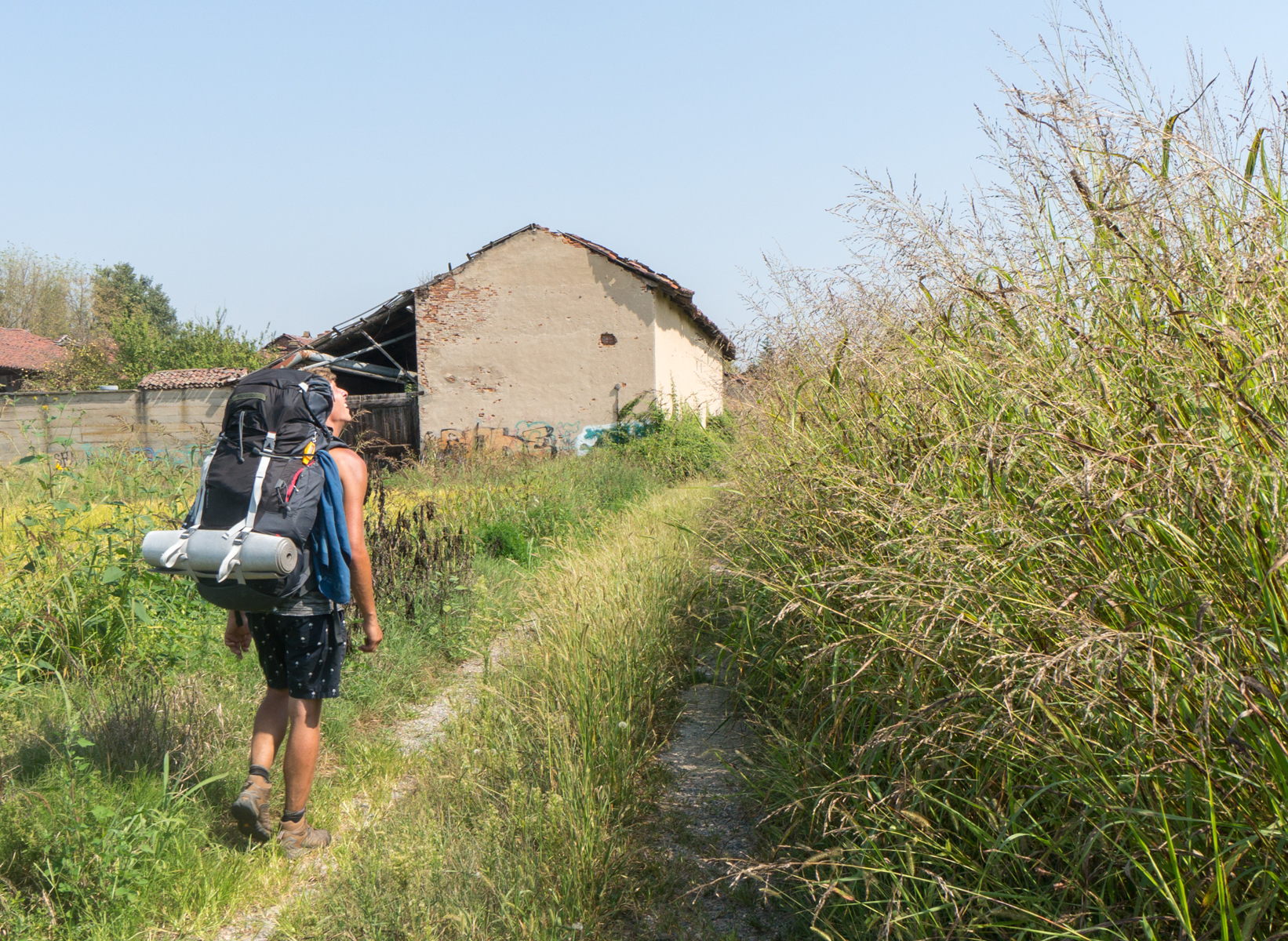 A pilgrim heads toward Vercelly, Italy, on Via Francigena as it passes through agricultural land | Photo by Mike Hudak